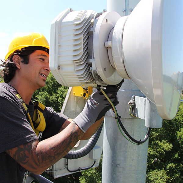 Techniker bei der Montage einer Richtfunkantenne am Mast vor Ort